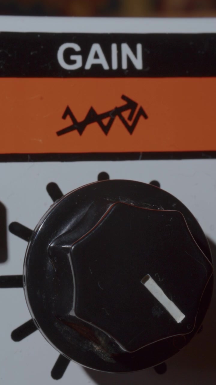 Extreme Close Up of Fingers Adjusting Gain Knob on Vintage Guitar Amplifier