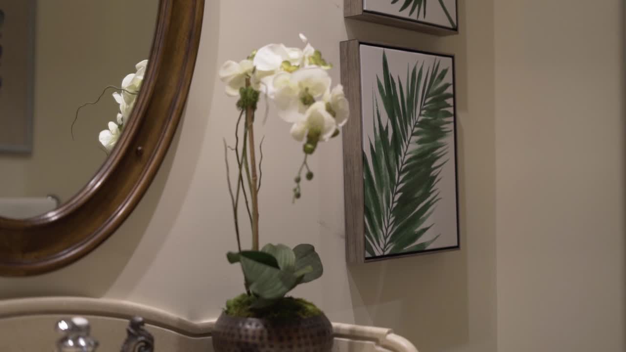 orchid in the bathroom in front of the mirror and pictures of tropical leaves