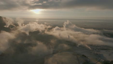 flying through cloudy steam over valley near hveragerdi at sunset in south iceland