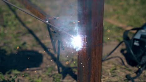 closeup handyman welds thin bottom rail to fence carcass