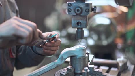 worker is measuring a produced detail by caliper.
