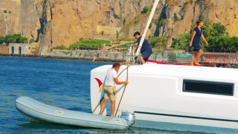 two people maneuvering a boat near rocky cliffs