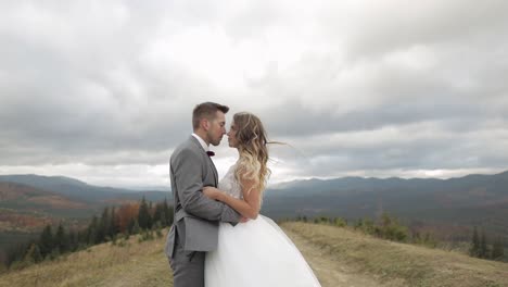 Lovely-young-newlyweds-bride-groom-embracing-on-mountain-slope,-holding-hands,-wedding-couple-family