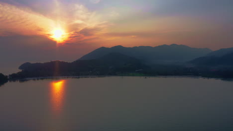 sun rising above hills and village on sea bay coast in koh chang