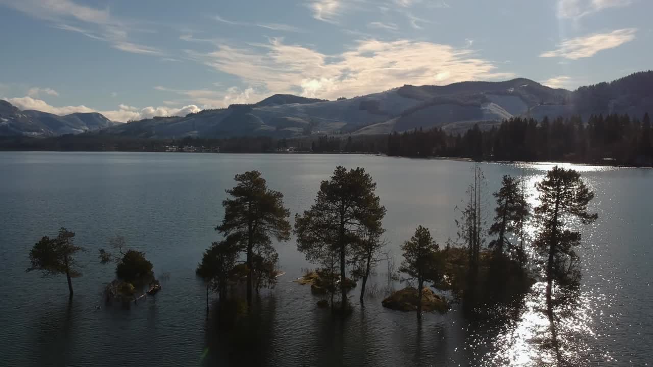 toma de drones del lago cowichan en la isla de vancouver, columbia británica, canadá, con vistas a la montaña helada, al lago, al bosque, a las pequeñas islas sumergidas y a la puesta de sol