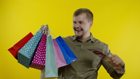 Man-showing-Up-To-70-percent-Off-inscription-and-shopping-bags,-looking-satisfied-with-low-prices