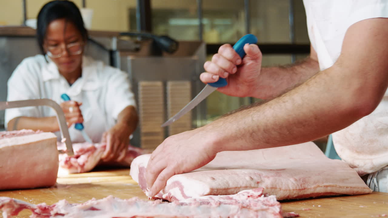Bearded butcher cutting meat for sale at a butcher's shop