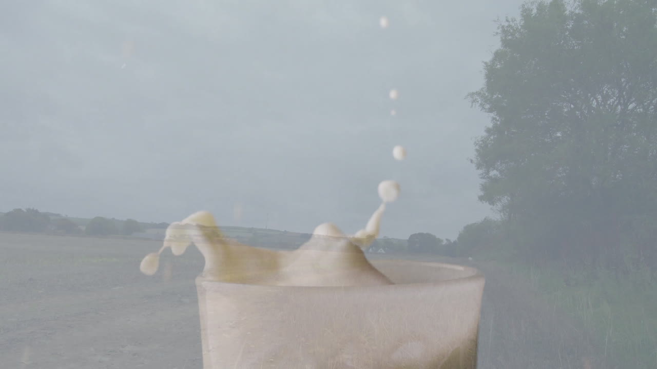 Splashing milk in glass with countryside landscape, trees, and cloudy sky animation