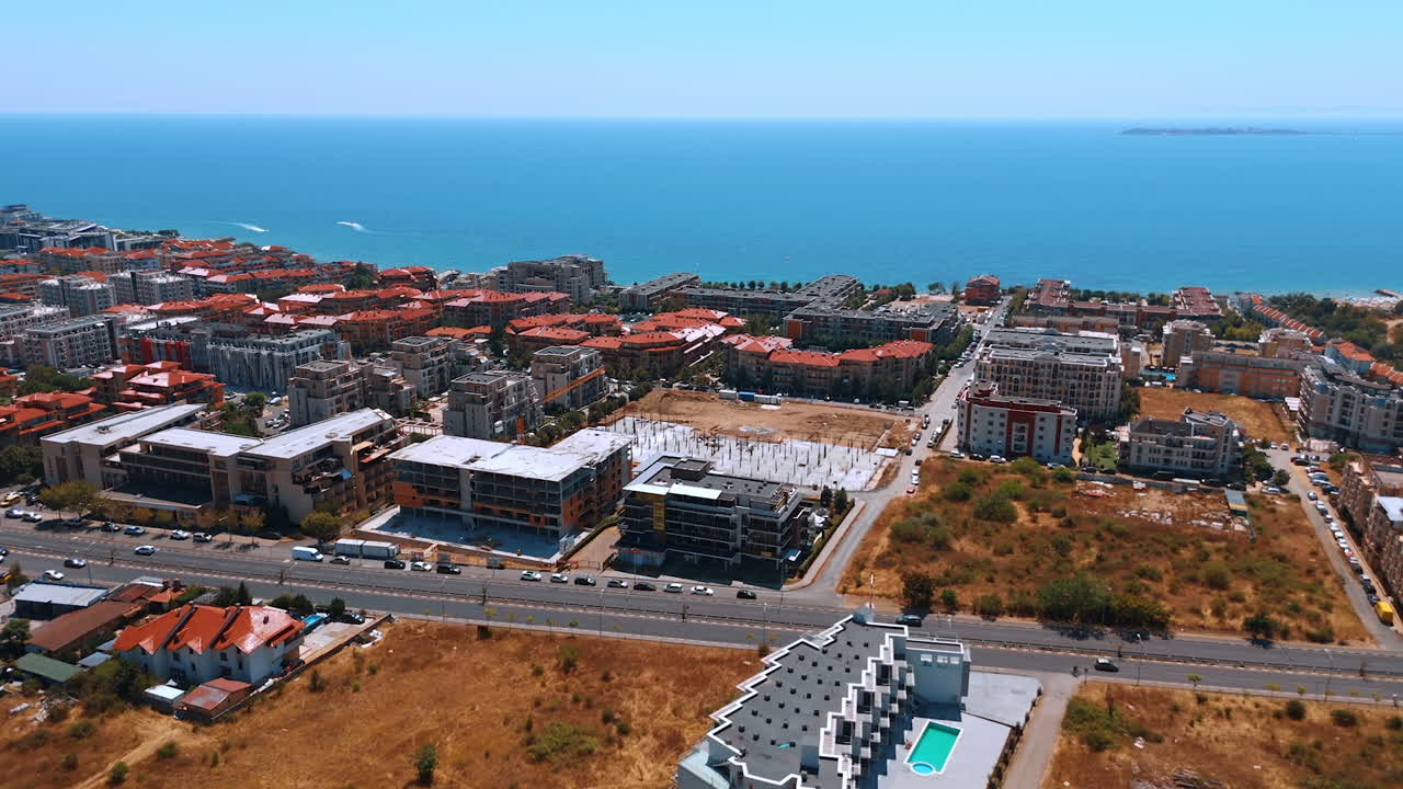 Aerial view of a modern coastal city with urban architecture. Drone shot of a modern coastal city showcasing residential buildings and the sea horizon