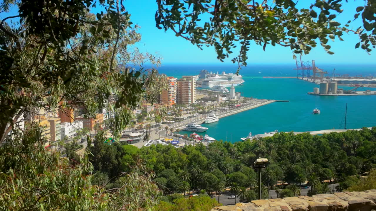 Close-up view of Málaga port from Gibralfaro, with the harbor filled with boats and lush greenery framing the scene under a sunny sky