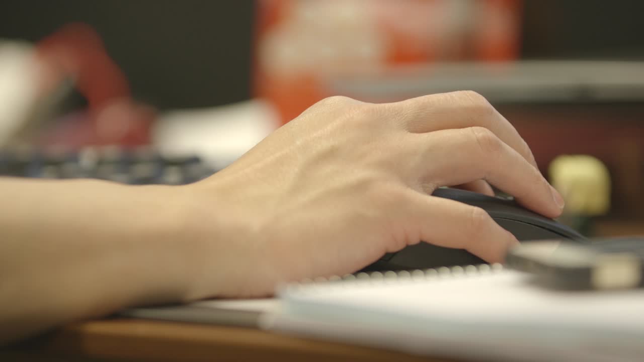 Close-up of a hand using a computer mouse on a desk