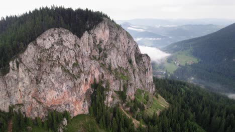 enormous rock face sticking out in the landscape, surrounded by forests, aerial