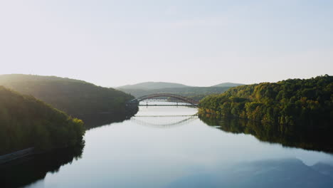 drone fly-in capturing the peaceful new croton reservoir with the iconic bridge reflecting on the still waters. framed by lush green hills in westchester, ny.