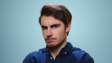 Unhappy-man-looking-at-camera-on-blue-background.-Upset-man-posing-in-studio