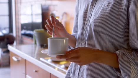 woman stirring coffee in kitchen at home 4k