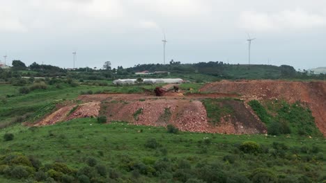 drone shot over hill with windmills and heavy machine