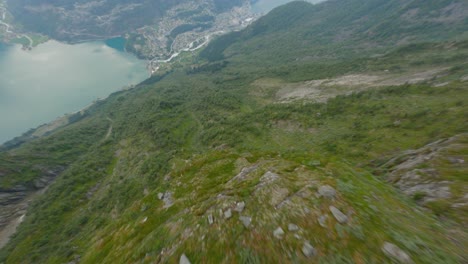 Vuelo-Aéreo-Cuesta-Abajo-Montañas-Verdes-Hacia-La-Ciudad-Turística-Odda-Y-Fiordo-En-Noruega---Disparo-Dinámico-De-Drones-Fpv---Montaña-Freimstolen-Rossnos