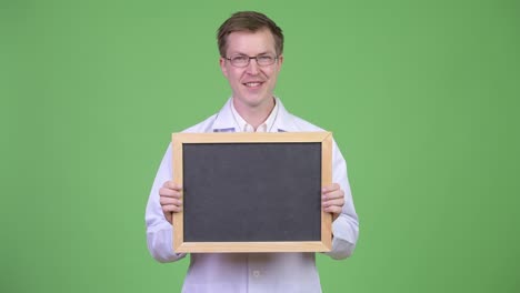 happy man doctor holding empty blackboard with copyspace