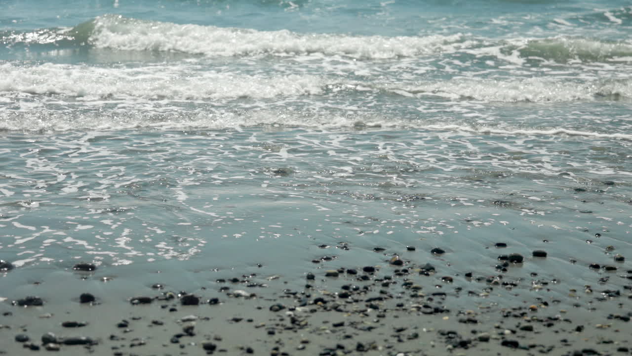 Slow motion footage of gentle waves rolling onto the sandy beach
