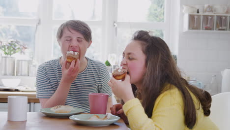 young downs syndrome couple enjoying tea and cake in kitchen at home