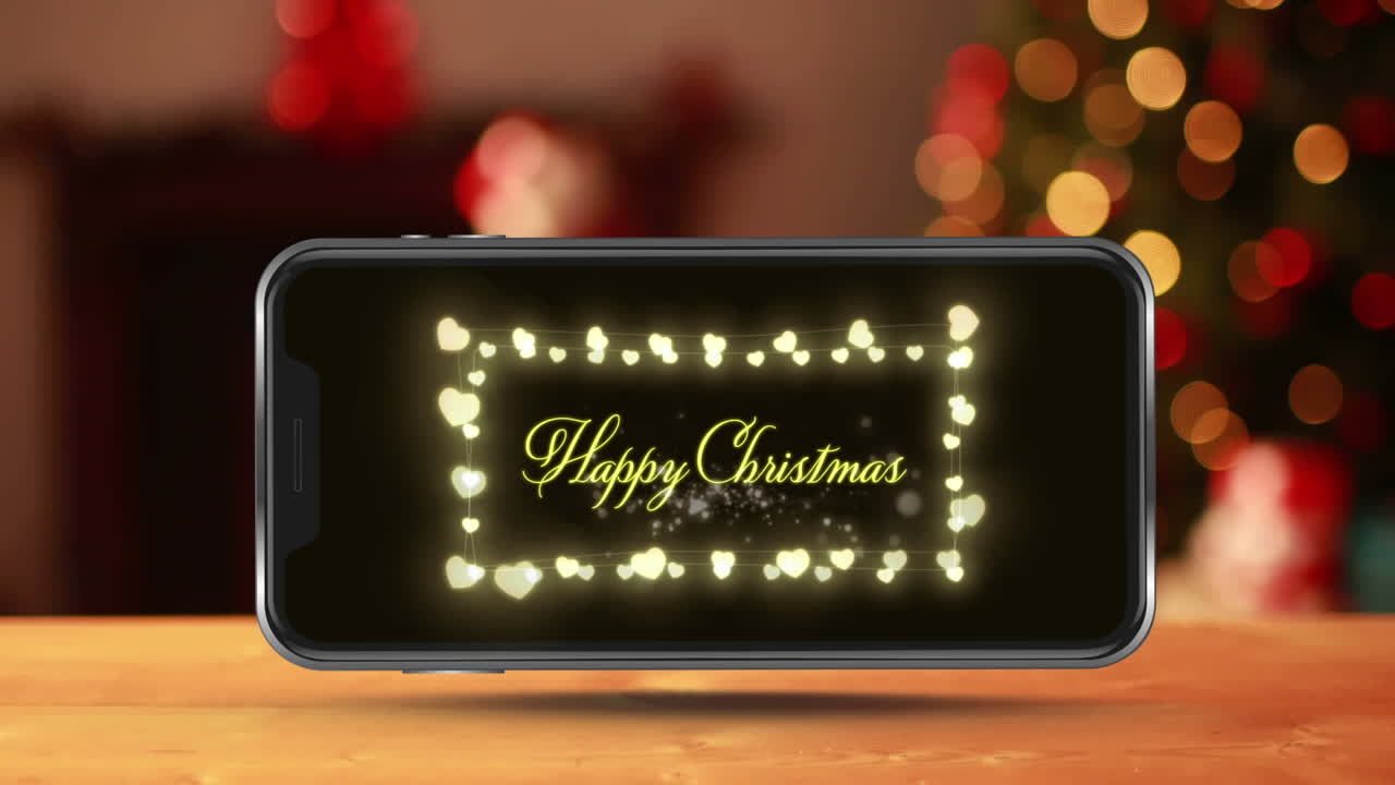 나무 표면에 스마트 폰 화면에 표시되는 행복한 크리스마스 텍스트와 요정 불빛의 애니메이션