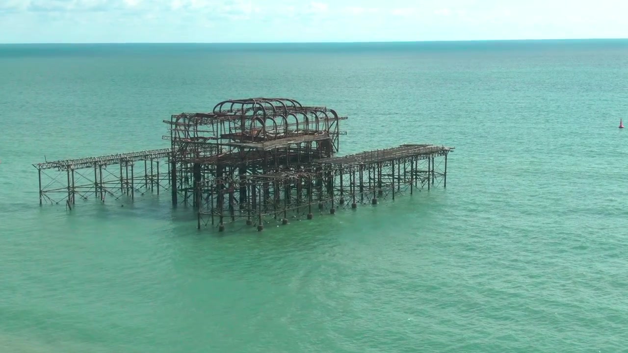 Tomada aérea de acompanhamento do antigo West Pier em Brighton. Píer abandonado. Horizonte como plano de fundo