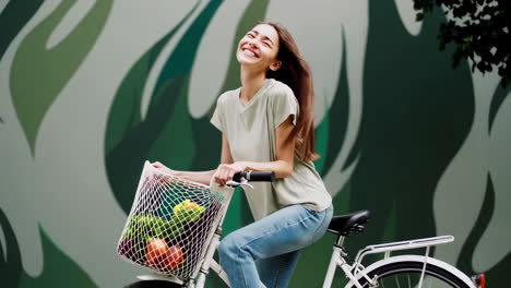 happy woman cycling with groceries in a mesh bag