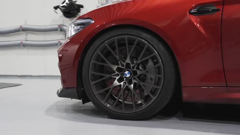 BMW-M2-luxury-car-expansive-wheel,-tire,-and-body-closeup,-BMW-in-reverse-gear-at-repair-shop