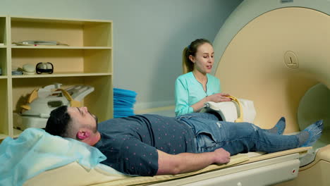 patient and female laboratory radiologist in modern clinic. male patient is lying in magnetic resonance image machine. advanced mri device in hospital.