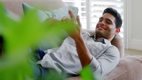 hombre feliz usando teléfono móvil en la sala de estar