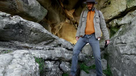 Male-hiker-walking-out-from-a-cave-4k