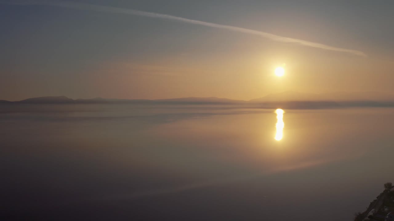 A serene and beautiful landscape of sun showing its reflection in the sea and giving a golden yellow color to the water scene. Aerial, sunset.