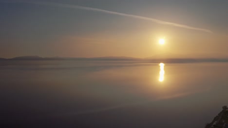 a serene and beautiful landscape of sun showing its reflection in the sea and giving a golden yellow color to the water scene. aerial, sunset.