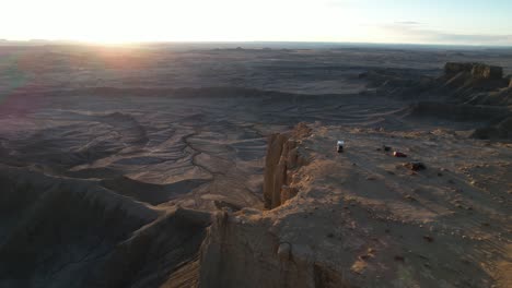 aerial view of vehicles on plateau with stunning view of sunset above desert landscape, drone shot