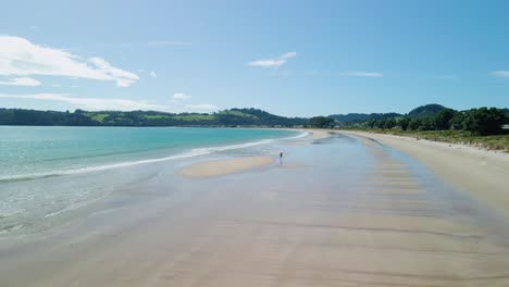 drone follows man running down the beach at low tide