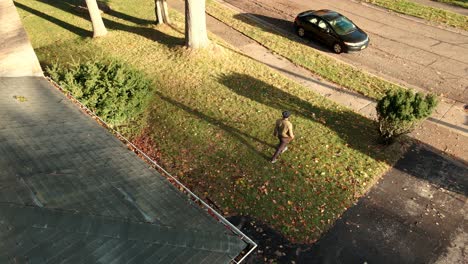 a man walks out and begins raking a front yard
