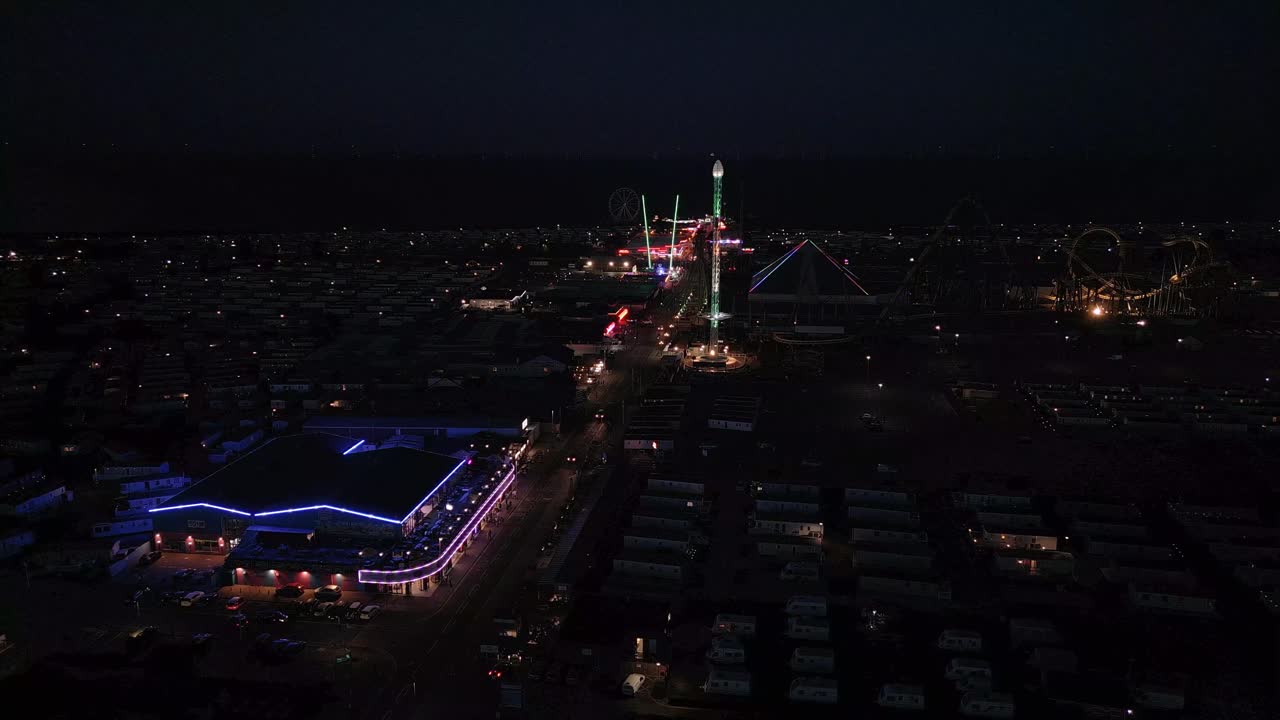 Evening aerial footage of a typical seaside amusement park. Fantasy Island amusement park at night in the seaside town of Ingoldmells near Skegness