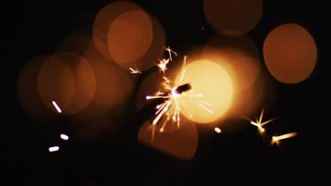 lit party sparkler sparkling on black background