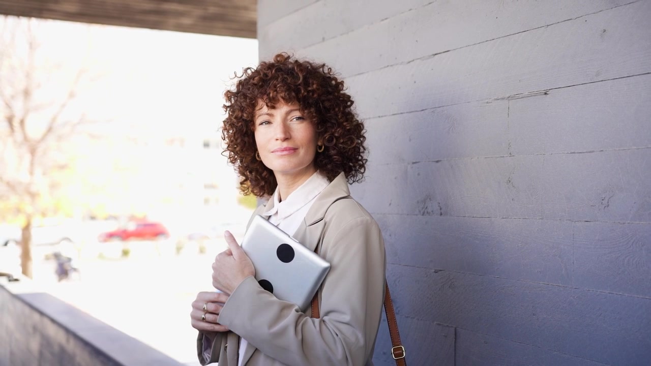Una donna professionista con bellissimi capelli ricci che tiene con sicurezza documenti importanti.