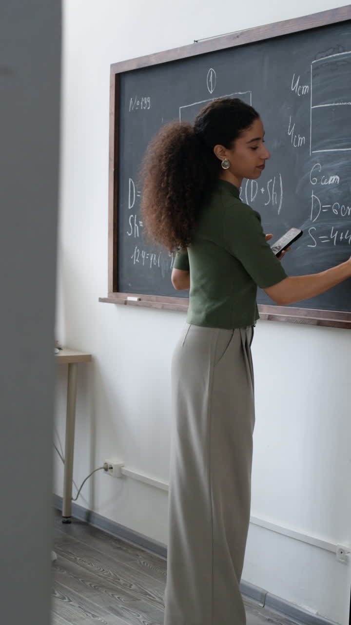 Teacher writing on chalkboard in classroom