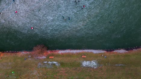 vista de pájaro de personas patinando sobre hielo en el lago, escena de invierno - toma de drone