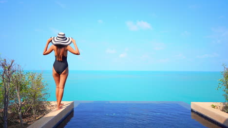 Back-View-Woman-Walking-on-the-Edge-of-Private-Infinity-Pool-Looking-at-the-Endless-Seascape-Daytime