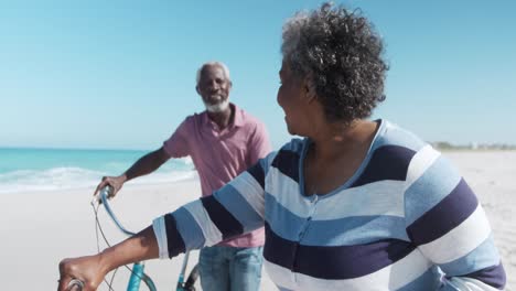 senior couple with bikes at the beach