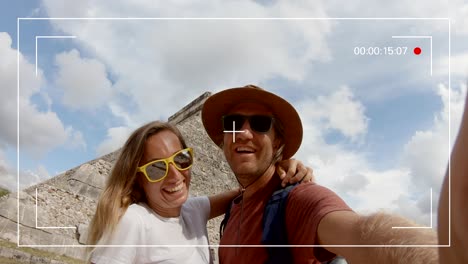 young couple taking selfie portrait in front of ancient mayan temple in mexico having fun exploring while on vacations. two people man and woman capturing a selfie in mexico