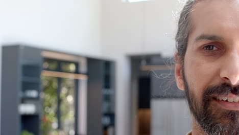 smiling man with long hair standing in modern kitchen at home, copy space