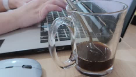 hands typing on a laptop, fueled by a fresh cup of coffee.