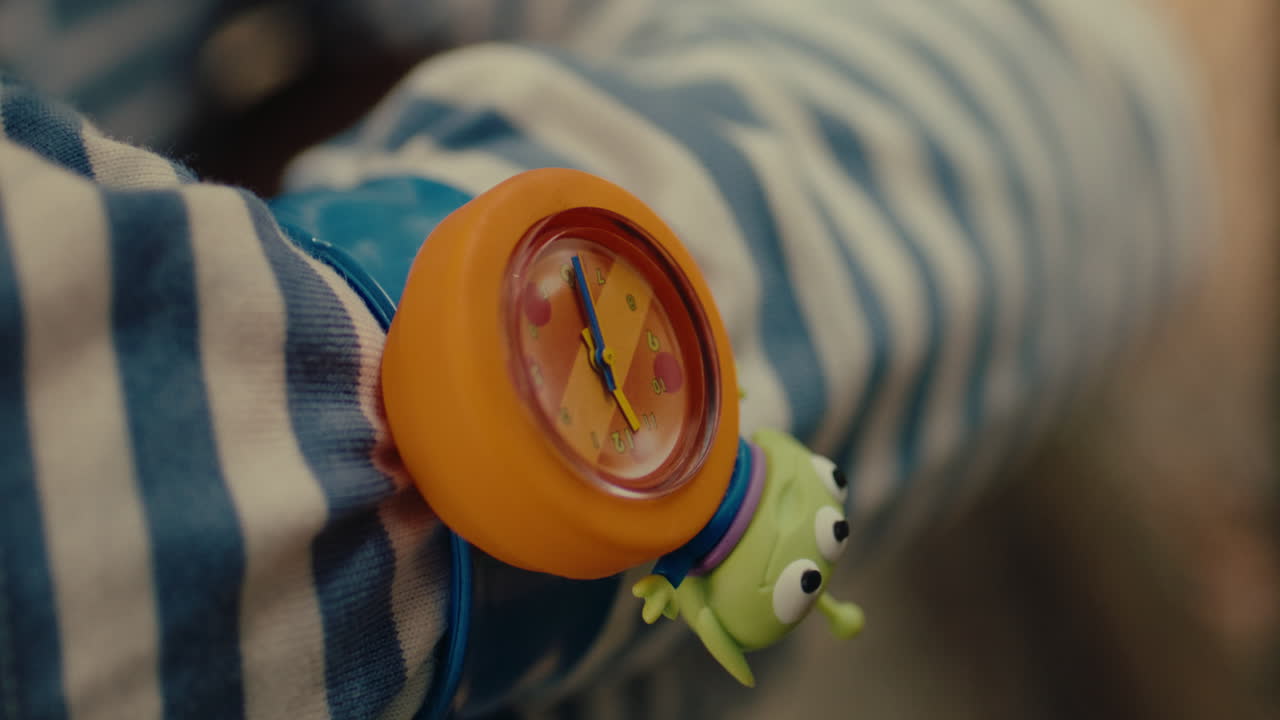 Child’s colorful toy watch with alien figure on striped sleeve, playful and bright