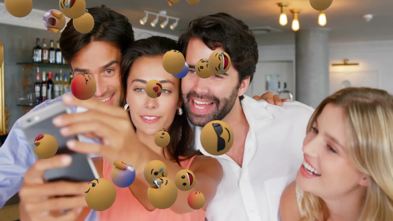 셀피를 찍고, 친구들이 떠다니는 이모지 애니메이션으로 둘러싸여 있습니다.