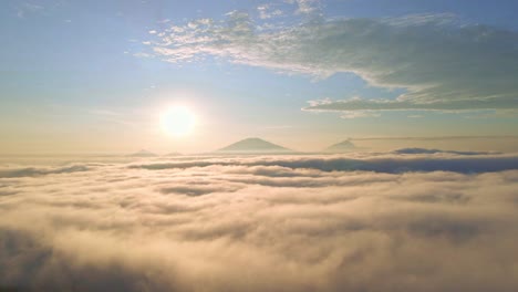 산의 실루 뒤에 밝은 해가 지고, 구름 위의 풍경