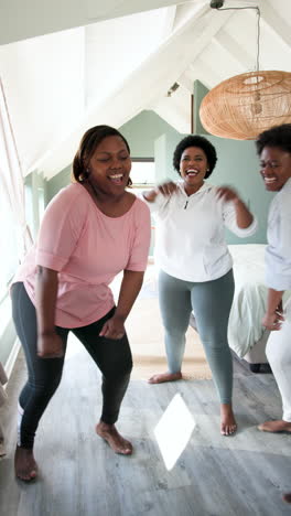 vertical video: african american women dancing joyfully at home, celebrating friendship together